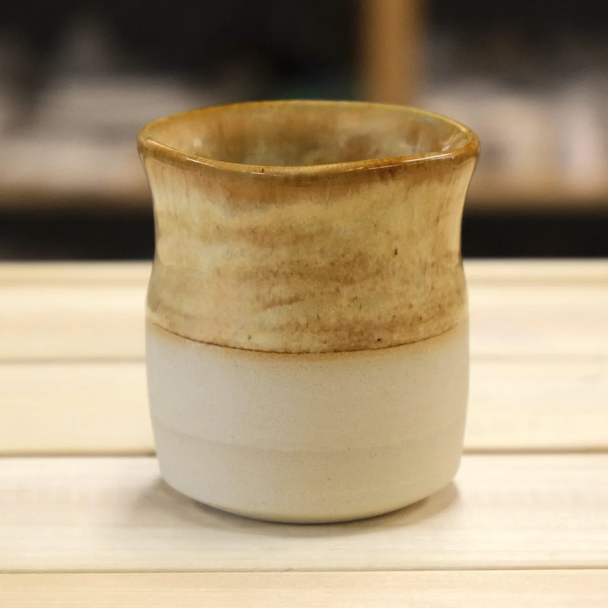 Handmade cup in a warm ochre glaze over a bare cream clay base.
