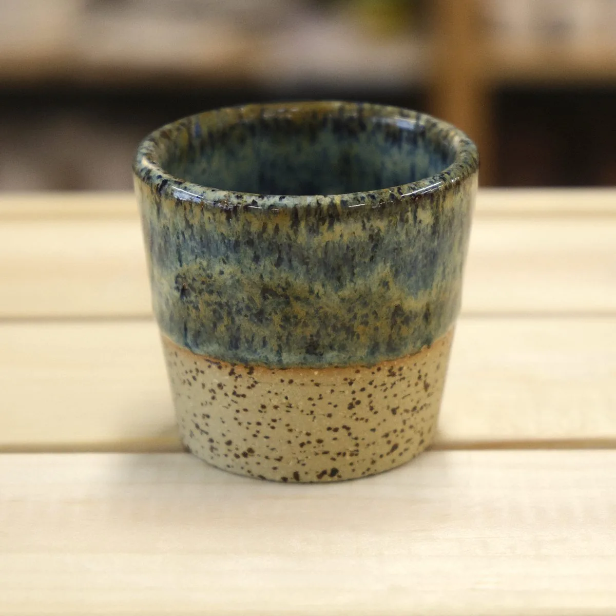 Handmade cup with an olive and blue speckled glaze over speckled stoneware.