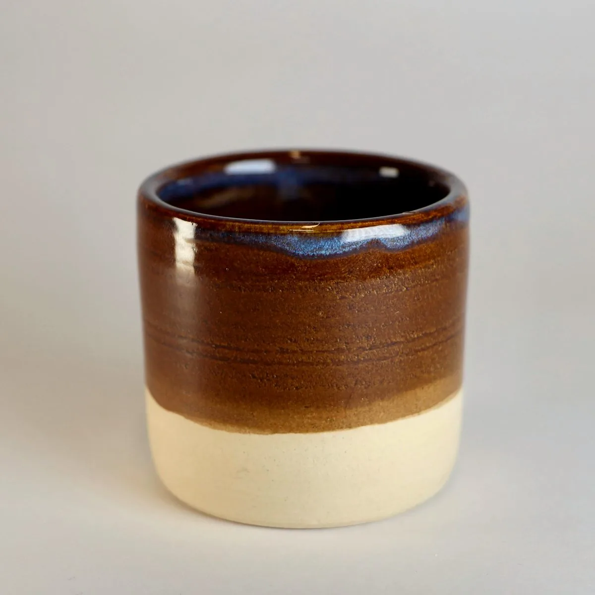 Handmade espresso cup in a deep coffee-brown glaze with a cream clay base.