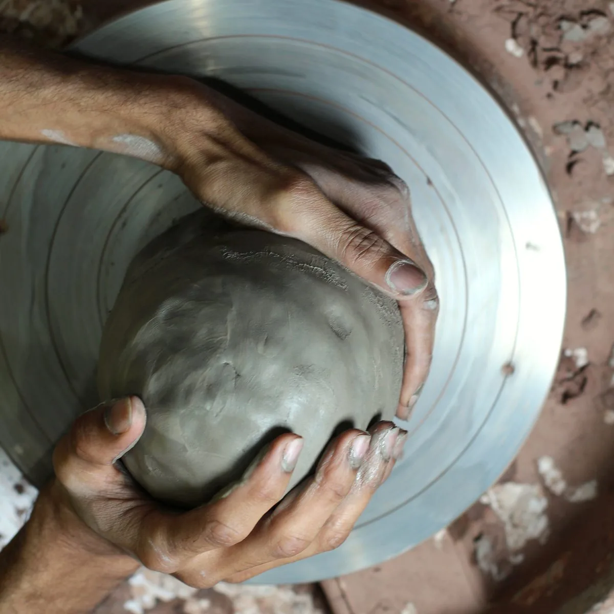 Clay: two hands centring a lump of wet clay on the potter's wheel.